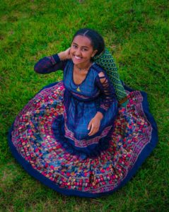 smiling brunette woman crouching in blue traditional dress