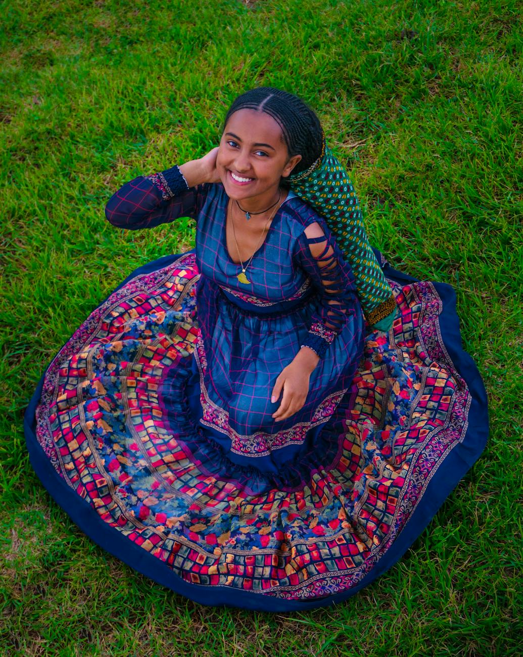 smiling brunette woman crouching in blue traditional dress
